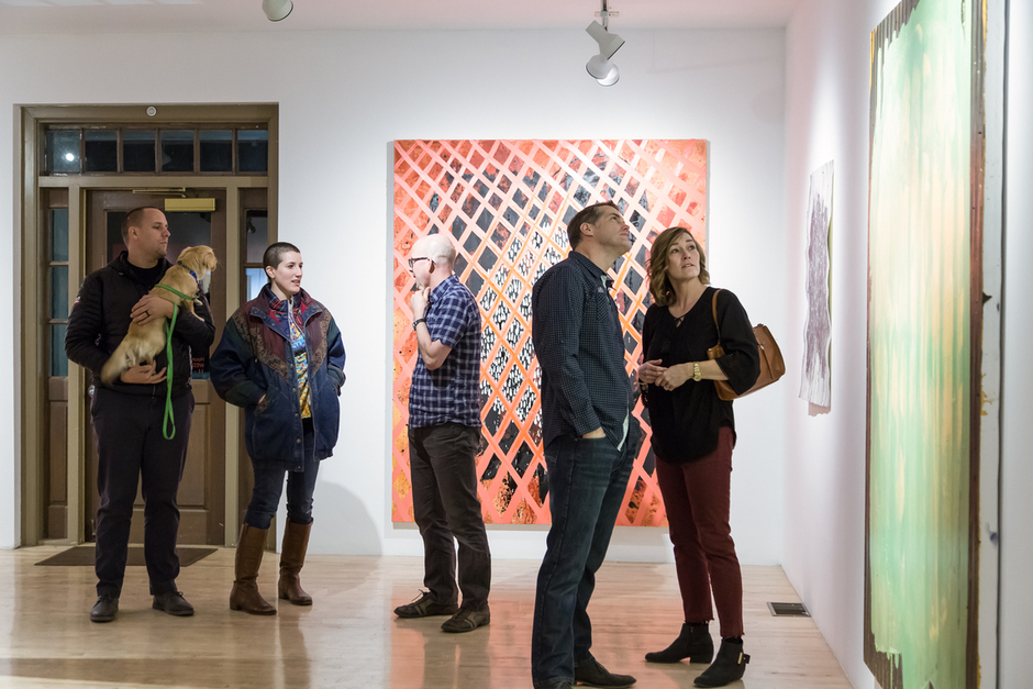 Gallery attendees look at artwork.