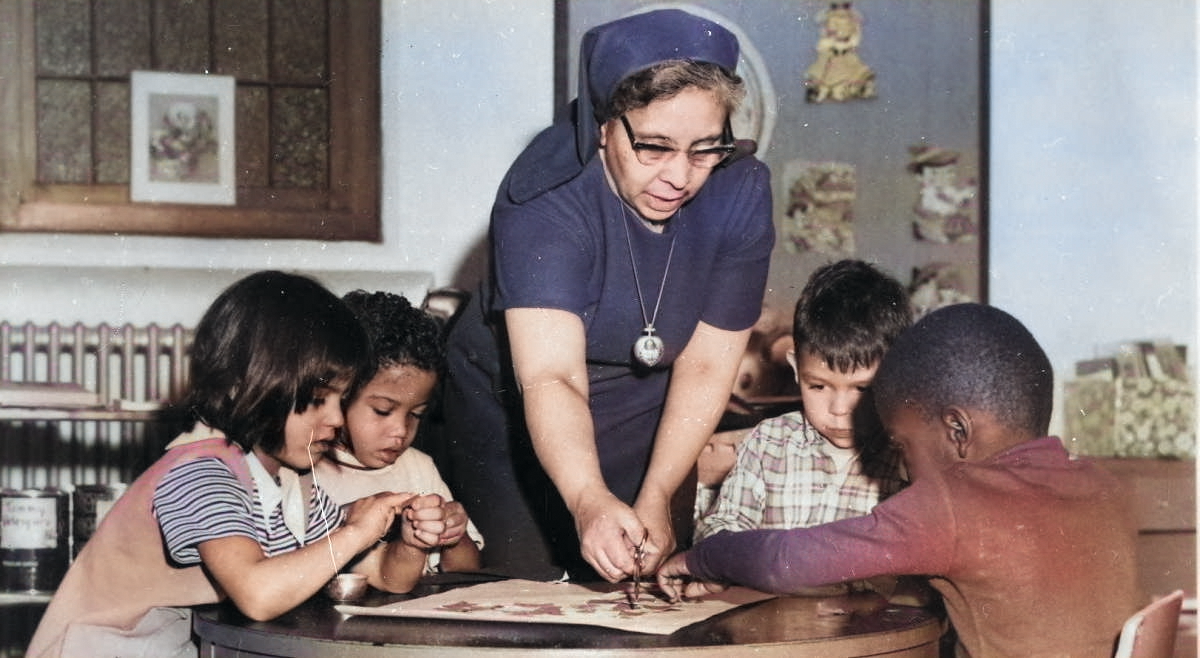 A dated photo of a teacher helping young students with a project